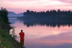 Monk walking along the Mekong